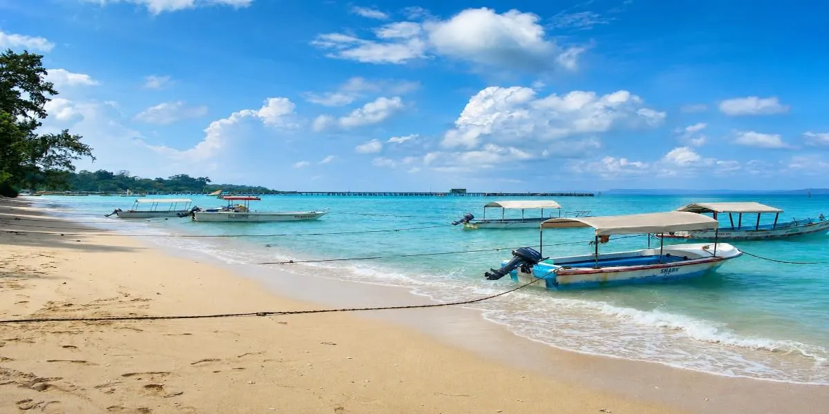 Boats drawn up on the sand with the jetty beyond