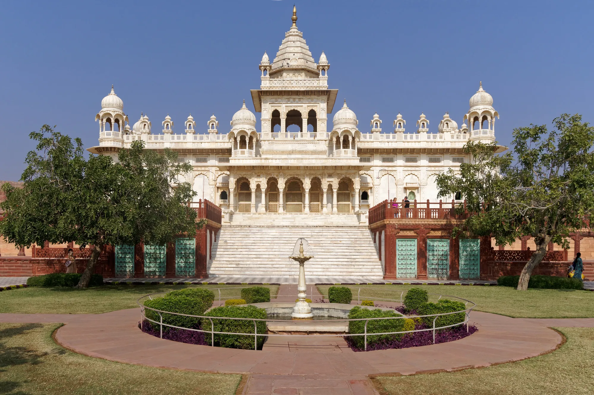 A white marble cenotaph with a formal garden in front of it