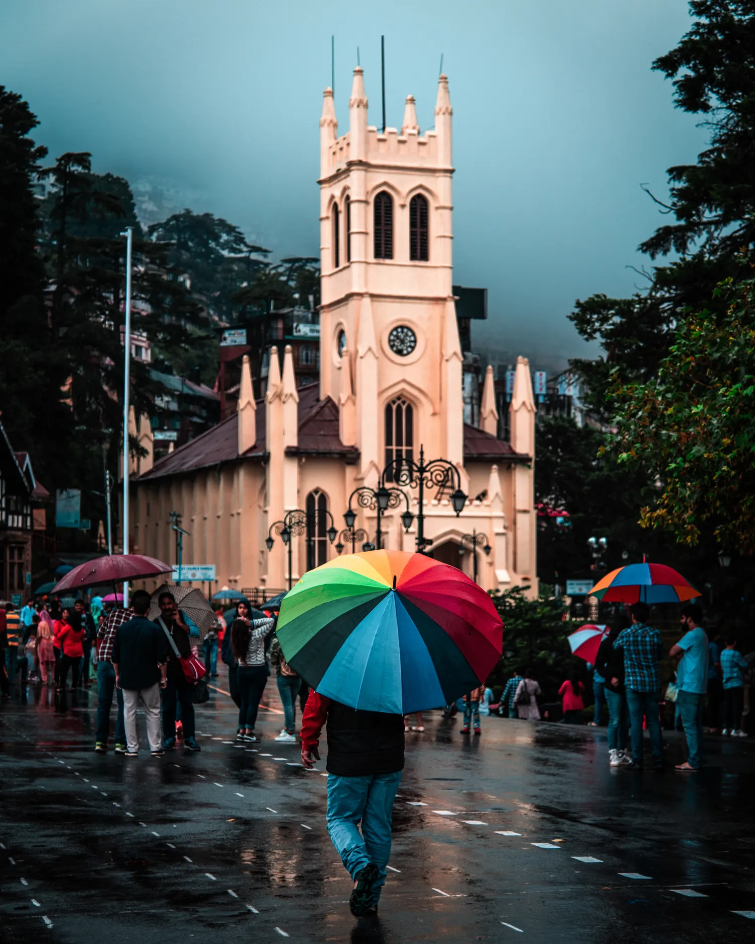 A church on a promenade in the rain with umbrellas in the foreground
